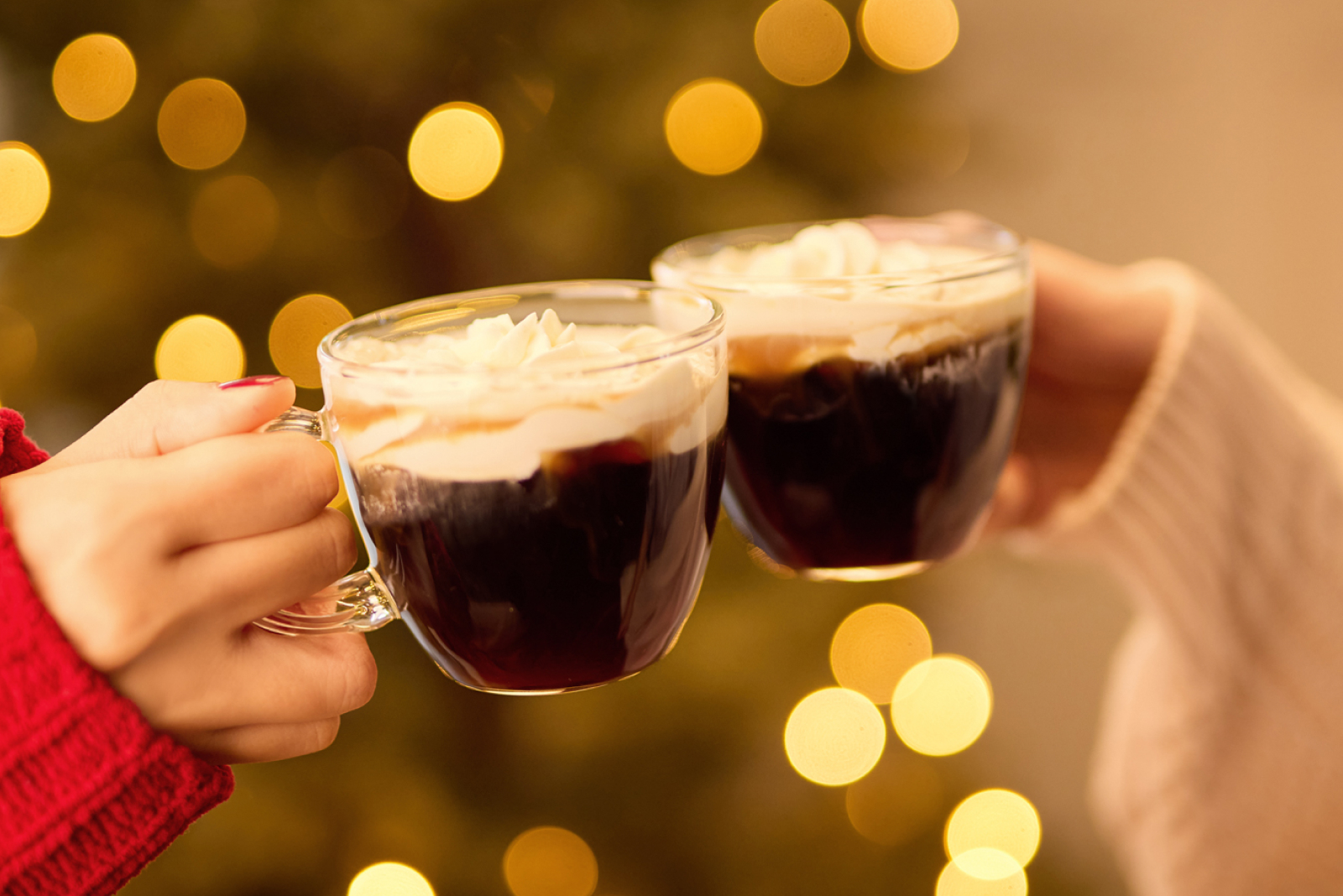 クリスマスツリーを背景に、アレンジコーヒーをいれたマグカップを片手に二人で乾杯をしている様子